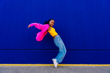 Happy Woman Dancing On Tiptoe By Blue Wall