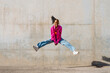 © VISTA by Westend61 - Happy dancer jumping in front of wall on sunny day