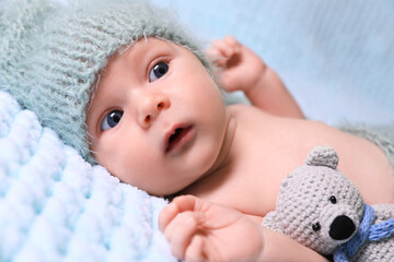 Canvas Print - Cute newborn baby with crochet toy on light blue blanket, closeup