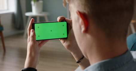 Wall Mural - Man using a smart phone with mock up green screen, talking while having an online conference - online education, communications concept close up