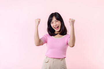 Portrait beautiful young asian woman happy smile with fist up victory gesture expression cheerful her success achievement against pink pastel studio background. Woman day winner celebration concept.
