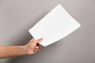 Wall Mural - man holding sheets of paper on grey background, closeup. mockup for design