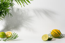 White Background With Palm Leaves, Lemon And Lime Slices. Modern Product Display For Advertising And Presentation Of Refreshing Summer Drinks, Natural Cosmetics
