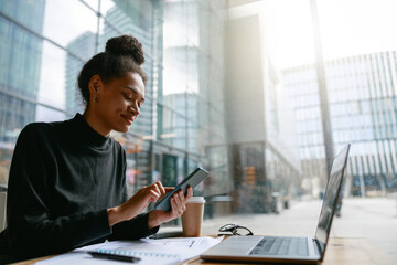 Smiling woman holding phone during working day in cafe sitting near window. Distance work concept