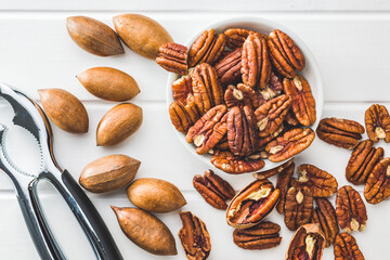 Poster - Peeled pecan nuts in bowl on white table. Top view.