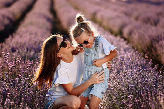 happy family in purple lavender field. young beautiful mother and child girl enjoy walking blooming 