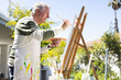 © Wavebreak Media - Happy senior caucasian man painting on easel in garden