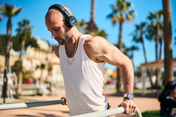 young guy exercising with calisthenics workout in an outdoor gym