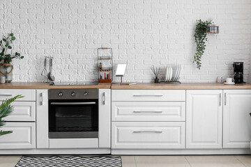 Canvas Print - Interior of light kitchen with white counters, electric oven and houseplants