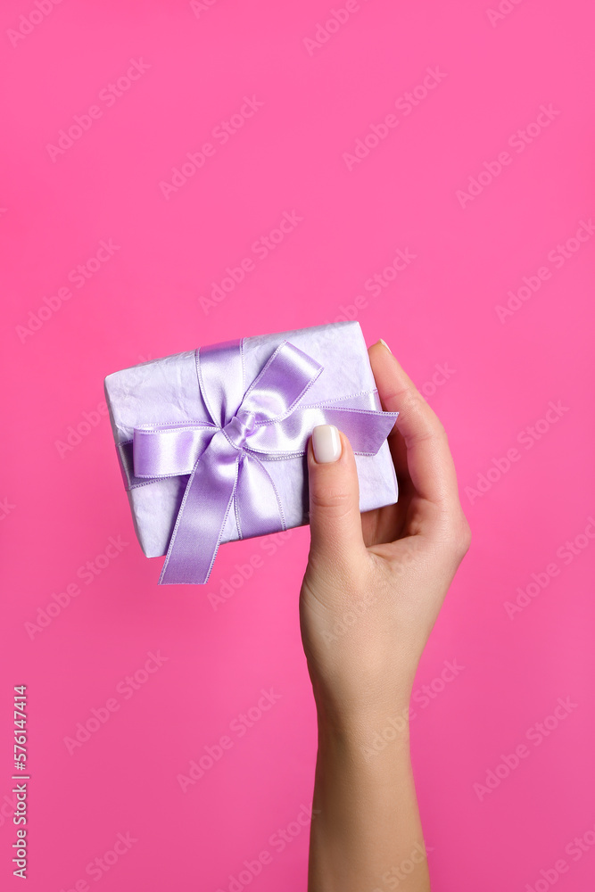 Woman with gift for Purim holiday on pink background