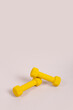 © Noemí Jiménez - Mancuernas de peso amarilla para ejercicios de resistencia, estiramientos, tenacidad con espacio para texto de gimnasio, fisioterapeutas ideal para poner horarios en fondo vertical neutro