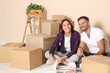 © New Africa - Happy couple surrounded by moving boxes choosing colors in new apartment