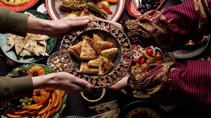 A woman passes a plate of fried samosa to a man. Dinner together. Authentic local homemade traditional meals in traditional dishes