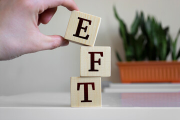 Wall Mural - Hand holding wood cube block with 'EFT' text.