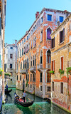 Canal with gondolas, antique buildings and sunburst, Venice, Italy. Venice is made up of 118 small islands connected by numerous canals and bridges