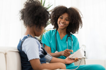 Female doctor or nurse using blood pressure gauge with child girl patient in the hospital