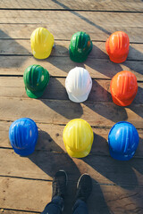 Wall Mural - Safety helmet (hard hat) for engineer, safety officer, or architect, place on wooden floor. Yellow, White, green, blue, and orange safety hat (helmet) on construction site-Vertical image.