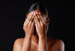 Hiding, shame and portrait of a woman covering face isolated on a black background in a studio. Shy, fear and girl with hands to cover eyes, an expression or insecurity about skin on a dark backdrop