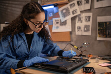 Female Engineer Fixing Broken Computer Motherboard In Workshop. Laptop Disassembling With Screwdriver At Old Repair Shop. Electronic Renovation, Technology Development