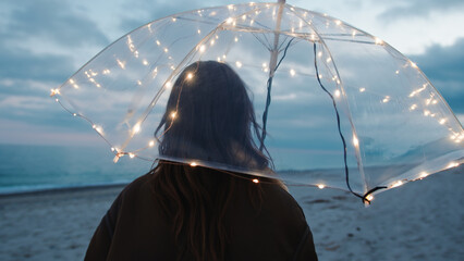 Wall Mural - Glowing umbrella of a girl walking on the beach in the night outdoor