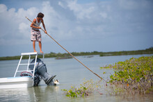 Man In Flats Boat Uses Pole To Push Off Mangroves