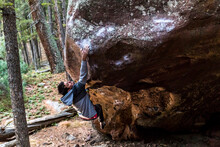 A Young Male Jumps For A Hold On A Boulder In Colorado