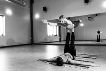 Two Fit Females Practice Acro Yoga Together Inside A Yoga Studio