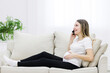 © Andrii - Side view of pregnant woman talking over the phone.