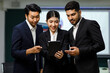 © Bangkok Click Studio - Millennial Asian professional successful female businesswoman employee in formal business suit stand smiling hold touchscreen tablet computer showing data information to male businessman colleagues