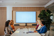 © bernardbodo - Businesspeople watching screen in meeting room.