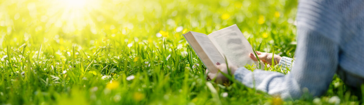Fototapete - Woman lying on the blossoming meadow with book in her hands.