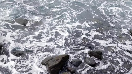 Wall Mural - Background of raging nature. The waves wash over the rocks. Water splash, foam. Power of nature.