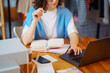 © maxbelchenko - Young female dress designer sitting at workplace with laptop. Small business owner, entrepreneur, seller checking ecommerce clothing store orders. Shopping concept. Fashion studio.