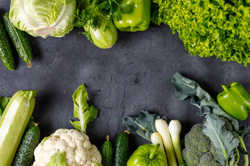 Wall Mural - Frame of green raw vegetables on black background. Top view of healthy organic food. Copy space