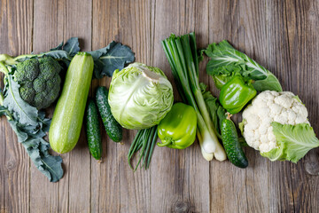 Wall Mural - Line of green raw vegetables on wooden background. Top view of healthy organic food. Copy space