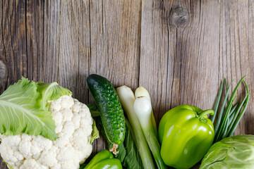 Wall Mural - Border of green raw vegetables on wooden background. Top view of healthy organic food. Copy space