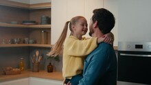 Adult Man Father Holding Spinning Lovely Daughter Spin Child Around Swirling Kid In Kitchen. Loving Dad And Little Girl Touch Noses Fooling Enjoy Bonding Hugging Embracing Cuddling Together At Home