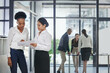 © AW/peopleimages.com - They work best when they work together. Shot of two female work colleagues discussing business in the office while their coworkers work in the background.