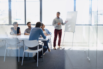 Wall Mural - Starting the day with a strategizing session. A businessman doing a presentation using a whiteboard during a boardroom meeting.