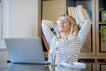 Healthy office lifestyle people concept. One happy and satisfied businesswoman stretching arms under her head and smile after finish the day of work at home office. Concept of success and relax