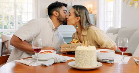 Poster - Interracial couple, gift and celebrate birthday being happy, kiss and smile in home at table with cake. Love, man and woman being content, romantic and present being cheerful celebration together.