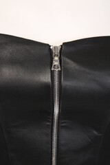 Wall Mural - Detail of a black leather garment with an accessory in the form of a button or zipper