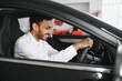 © Serhii - A young Indian man chooses a new car at a car dealership