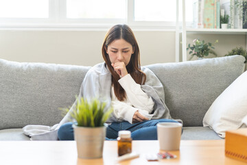 Wall Mural - Sick, hurt or pain asian young woman, girl with sore throat, cough have a fever, flu and sneezing nose, runny sitting on sofa bed at home. Health care person on virus seasonal.