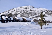 Snowy Scenes In Hovden, Norway. Ski Tracks On The Ground, With Mountains And Trees Behind. Snow Covered Houses And Blue Skies. Bluebird Weather. 