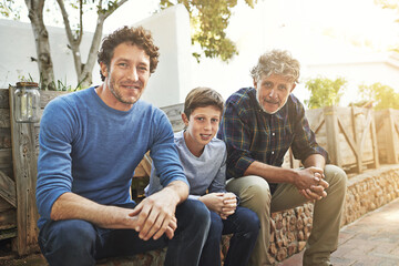 Sticker - Family is everything. Portrait of a young boy sitting with his father and grandfather in their backyard.