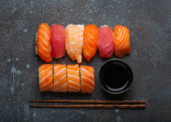 Wall Mural - Set of traditional Japanese sushi and rolls top view with soy sauce and chopsticks on rustic stone background. Sushi with salmon, tuna and shrimp