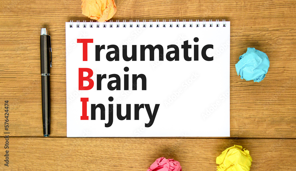 TBI traumatic brain injury symbol. Concept words TBI traumatic brain injury on white note on a beautiful wooden table wooden background. Pen. Medical and TBI traumatic brain injury concept. Copy space
