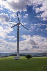 Wind power plant in landscape with turbine between the clouds at blue sky