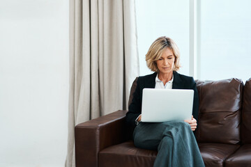 Canvas Print - Keep up to date on the latest trends in psychotherapy. Shot of a mature psychologist sitting on a sofa and using a laptop.